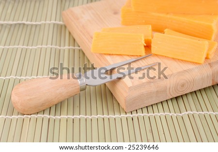 blocks of cheddar cheese on a wooden block with cheese cutting  accessories