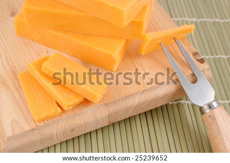 blocks of cheddar cheese on a wooden block with cheese  accessories