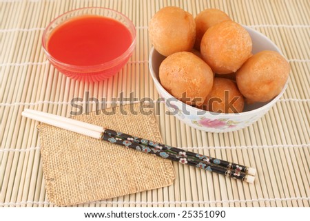 fried and crispy chinese food chicken balls with chopsticks and cherry dipping sauce