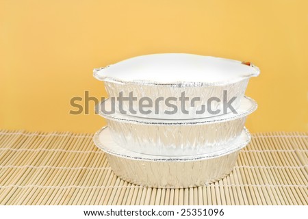 chinese food delivery or takeout aluminum covered containers on bamboo placemat