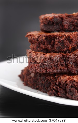 Pile of  chocolate fudge brownies on a plate with a grey  background (short depth of field)