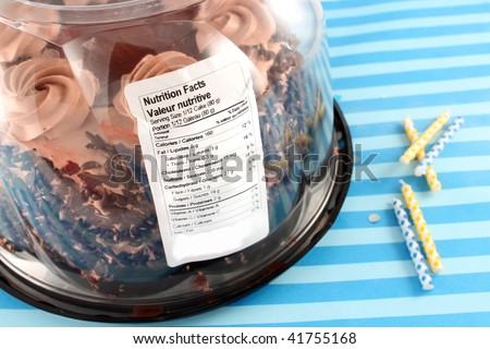 Black Forest Chocolate cake in package containing nutritive value label with birthday candles on blue striped background