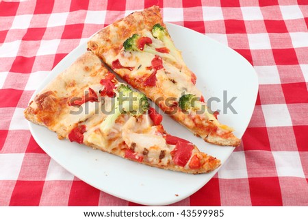 Two slices of red peppers, broccoli and grilled chicken pizza with red checkered table cloth background