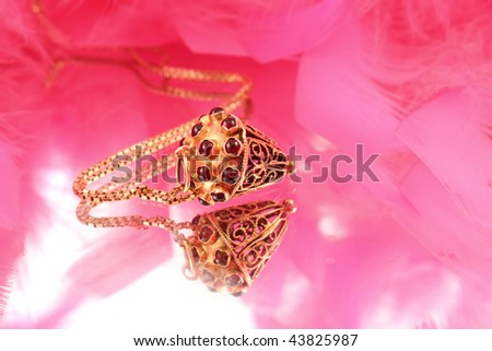 Gold necklace and charm in the shape of an acorn with embedded garnets signifying a january birthdate