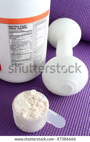 A scoop of vanilla powder protein with dumbell in the background and container showing nutritional facts on a purple exercise mat.