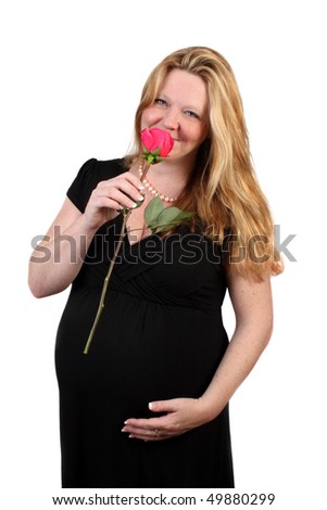 Pretty Irish woman with blonde hair in her third trimester touching her pregnant belly dressed in a black on a white background holding a rose