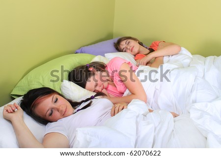 stock photo Three pretty teenage girls sleeping on a bed at a sleepover or 