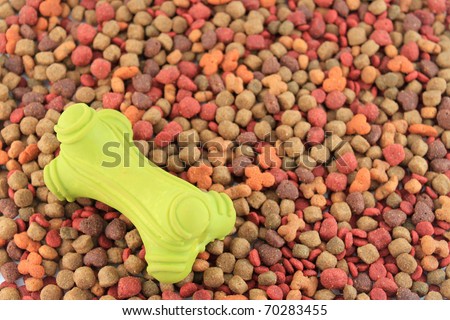 A green rubber dog toy on a background of dog food bits