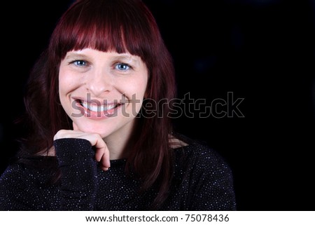Pretty smiling redhead woman with sparkly shirt on a black background