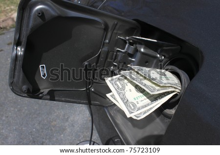 Money sticking out of car\'s gasoline tank showing the rising cost of fuel