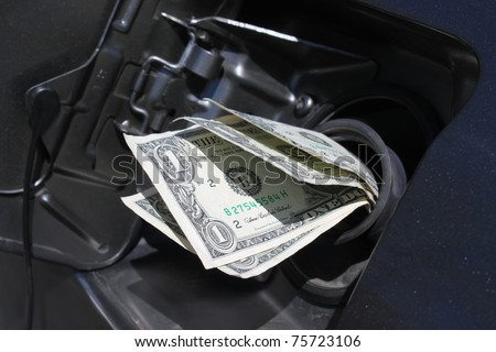 Money sticking out of car\'s gasoline tank showing the rising cost of fuel