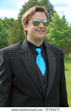 Handsome, smiling young man wearing a formal suit and mirror glasses going to the prom or a groom at a wedding
