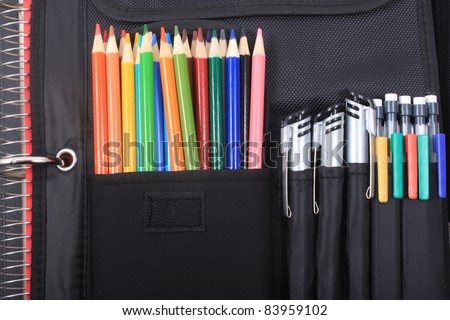 Colorful sharpened  pencil crayons for school in three ring binder pocket with pens on the side