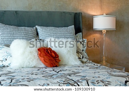 Close up of a luxury set of bedding in black and white patterns with a red accent flower on a bed in natural light