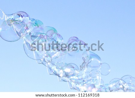 Stream of Iridescent bubbles against a blue sky