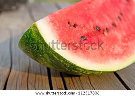 Corner angled view of red watermelon with black seeds on vintage wood table