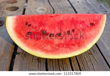 Side view of red watermelon with black seeds on vintage wood table