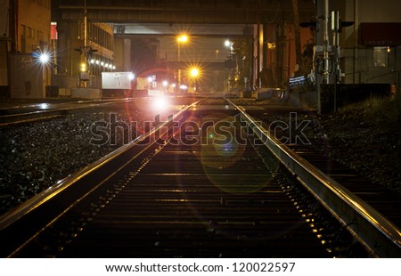 Shiny wet train tracks reflecting lights at night