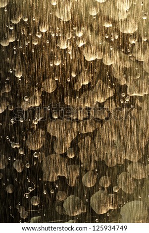 Vertical background of water patterns on bronze streaked metal