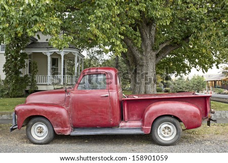 Cheerful vintage red truck parked in front of white Victorian home