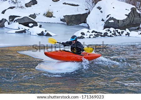Man sitting on top of an ice flow in an orange kayak