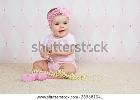 Little girl sitting on the floor holding a pearl necklace