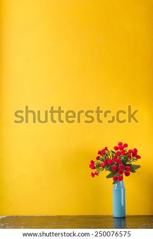 Red flowers in vase on yellow background