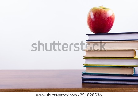 An apple on a stack of colorful books and chalk. Back to school.