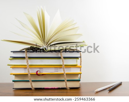 Stack of colorful books tied with a rope, open book and an apple. Back to school on white background. Copy space for text.