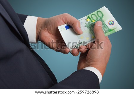 Businessman counts money on blue background. Hand holding money.