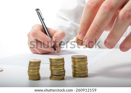 Business concept. Businessman\'s hand counting money on calculator and signing documents at office workplace, office work. Stack of coins. Financial Accounting - money and calculator.