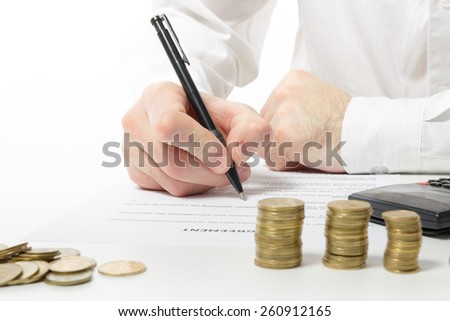 Business concept. Businessman\'s hand counting money on calculator and signing documents at office workplace, office work. Stack of coins. Financial Accounting - money and calculator.