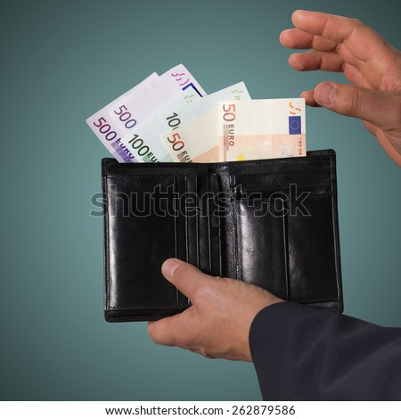 Euro banknotes in the black wallet isolated on blue background. Man holding wallet with money.