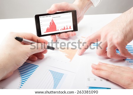 Business people on a meeting analyzing financial reports discussing the charts and graphs showing the results of their successful teamwork