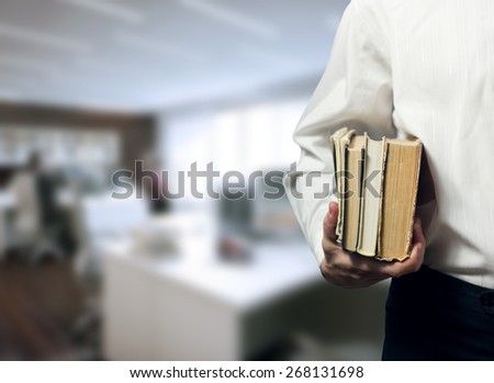 Man holding books on blurred office background. Finding a job, looking for a job concept.