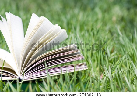 Open book, fanned pages on grass. Summer spring backgound with open book. Back to school.  Copy Space