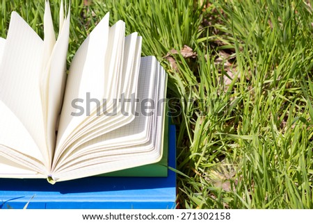 Open book, fanned pages on grass. Summer spring backgound with open book. Back to school.  Copy Space