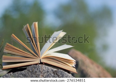 Open hardback book, fanned pages on grass. Summer spring background with open book. Back to school. Copy Space. Education background.