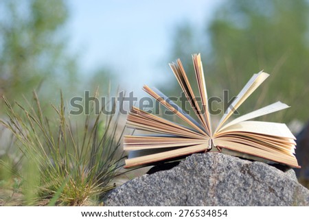 Open hardback book, fanned pages on grass. Summer spring background with open book. Back to school. Copy Space. Education background.