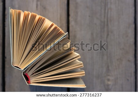 Open hardback book, fanned pages on wood planks. Summer spring background with open book. Back to school. Copy Space. Education background.