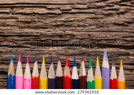 Row of colored drawing pencils closeup on old grunge natural wooden shabby desk background. Vintage stylized image. Copy space