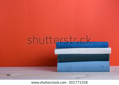 Composition with vintage old hardback books, diary, fanned pages on wooden deck table and red background. Books stacking. Back to school. Copy Space. Education background.