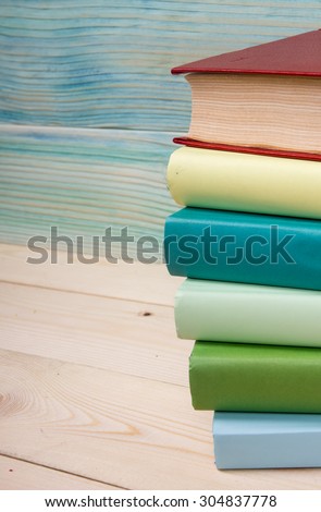 Back to school. Stack of colorful books on grunge blue green wooden background. Composition with vintage old hardback books, apple, pen, pencil,  Books stacking. Copy Space. Education background.
