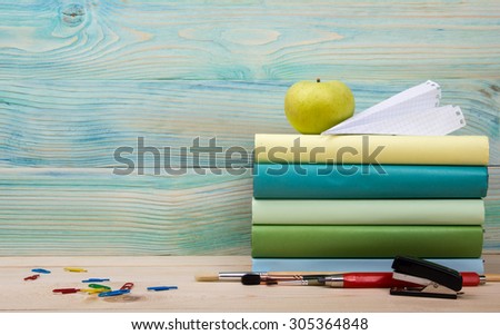 Back to school. Stack of colorful books on grunge blue green wooden background. Composition with vintage old hardback books, apple, pen, pencil,  Books stacking. Copy Space. Education background.