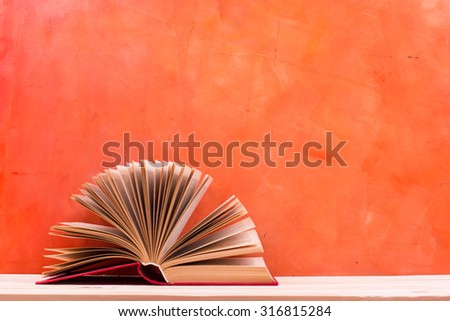 Composition with vintage old hardback books, diary, fanned pages on wooden deck table and red background. Books stacking. Back to school. Copy Space. Education background