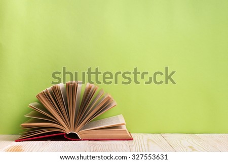 Composition with vintage old hardback books, diary, fanned pages on wooden deck table and green background. Books stacking. Back to school. Copy Space. Education background