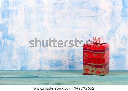 Gift box with red bow on vintage blue wooden table background. Christmas decoration on grunge blue artistic painted background. Winter holidays concept. Copy space. Merry Christmas and Happy New Year!
