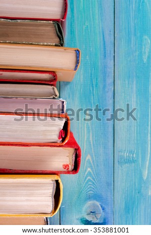 Composition with old vintage colorful hardback books, diary on wooden deck table and artistic blue background. Books stacking. Back to school. Copy Space. Education background