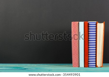Raw of old vintage colorful hardback books, diary on wooden deck table and black board chalk wall background. Books stacking. Back to school. Copy Space. Education background
