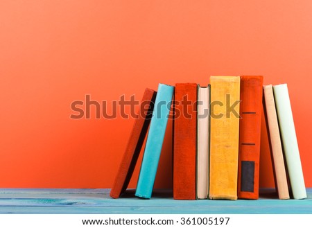 Raw of old hardback books, diary, on wooden deck table and red background. Books stacking. Back to school. Copy Space. Education background.
